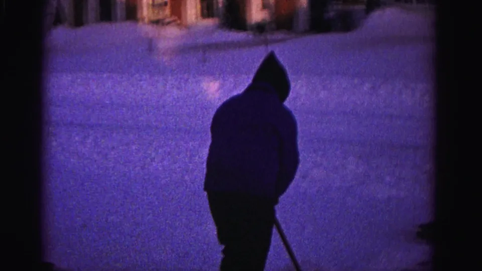 Silhouetted hooded man with snow shovel on residential driveway, deep purple color cast, 8mm home movie, Hagerstown Maryland area, circa 1962.