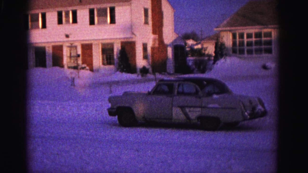 Early 1960s 8mm home movie — large tan sedan in snow-covered driveway, white clapboard house with brick chimney, Hagerstown MD area, 1962.