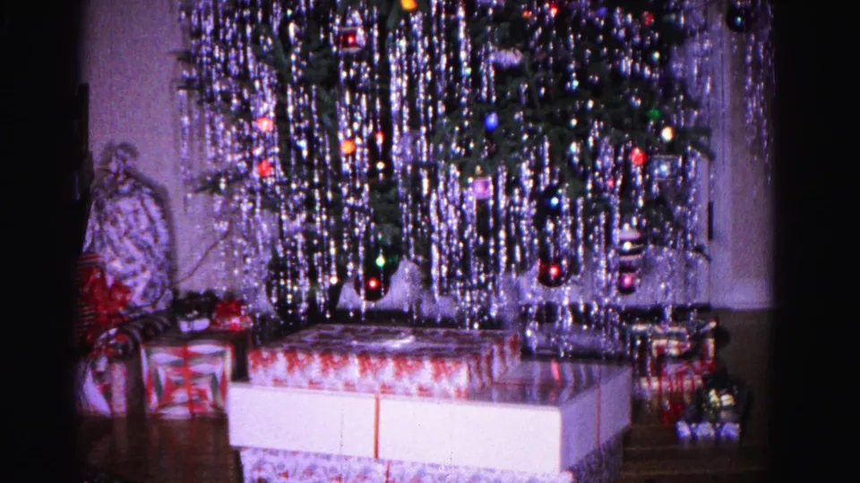 Aluminum tinsel Christmas tree with colored lights and ribbon-wrapped gifts, in a domestic living room interior, circa 1962, Hagerstown, Maryland.