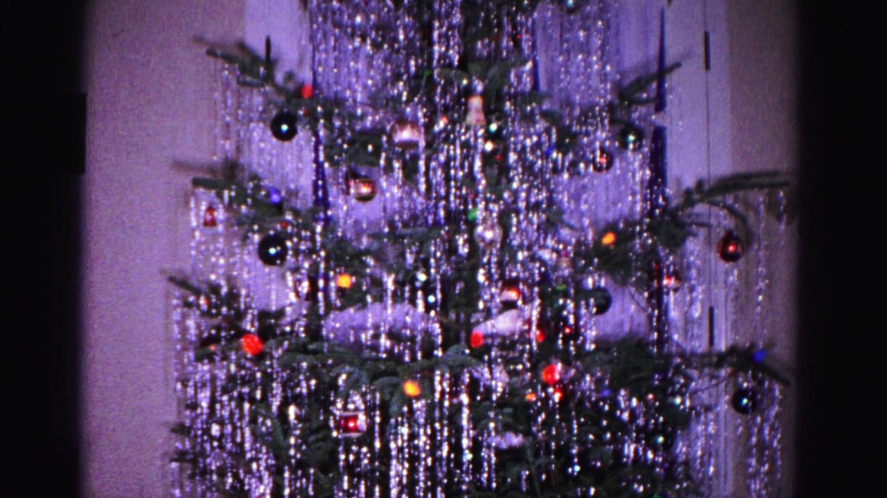1962 8mm home movie: Christmas tree with cascading silver tinsel, colorful ball ornaments, and string lights in a domestic interior, Hagerstown, Maryland.