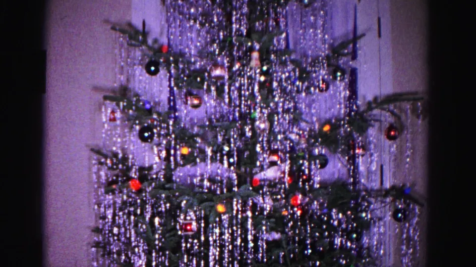 1962 8mm home movie: Christmas tree with cascading silver tinsel, colorful ball ornaments, and string lights in a domestic interior, Hagerstown, Maryland.