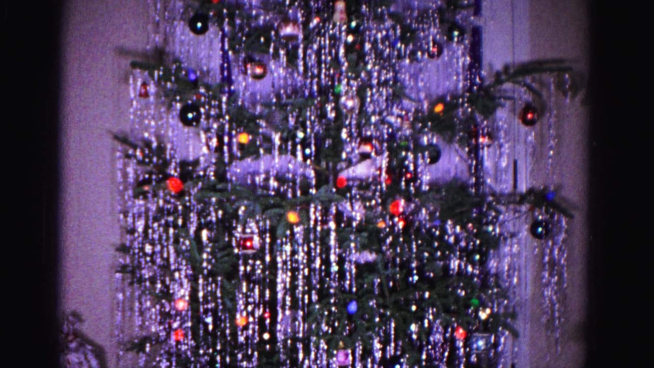 1962 8mm home movie: Christmas tree with cascading tinsel and round ornaments against a lavender-tinted interior wall, Hagerstown, Maryland.