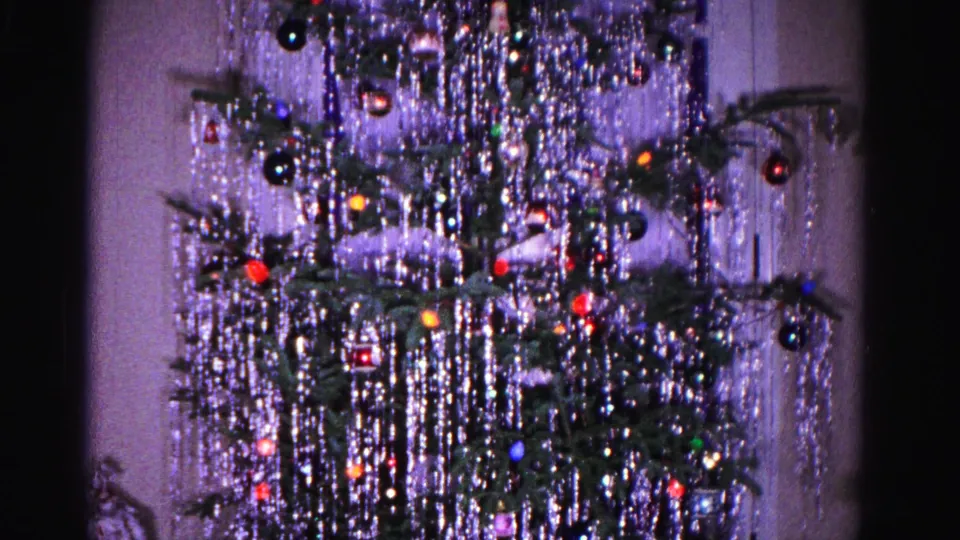 1962 8mm home movie: Christmas tree with cascading tinsel and round ornaments against a lavender-tinted interior wall, Hagerstown, Maryland.