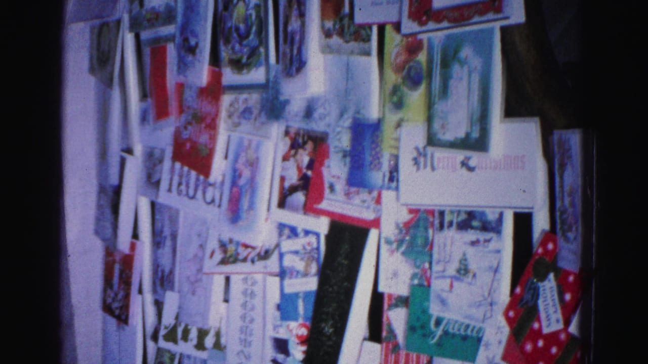Christmas greeting card collage on a wall, 8mm archival footage, Hagerstown Maryland circa 1962; Noel text and Christmas tree illustrations visible.