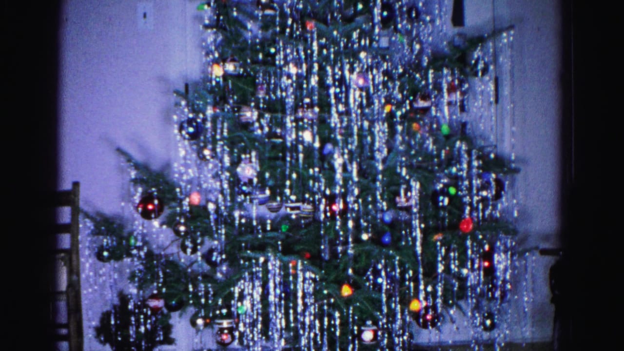 Christmas tree with heavy silver tinsel and colored ornaments, interior domestic setting, 8mm film