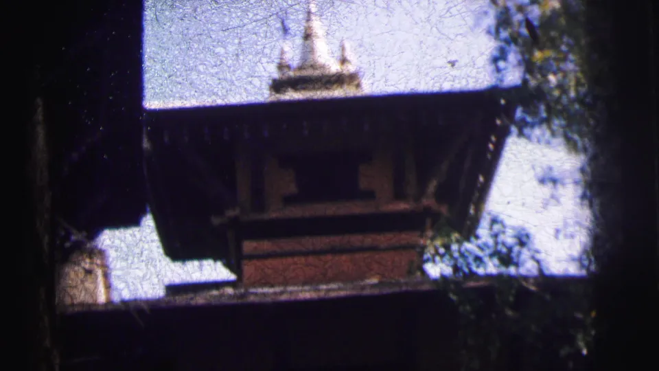 8mm frame from a 1962 Calcutta home movie showing ornamental white finials atop a multi-tiered religious structure against a bright open sky, with visible film crackle.