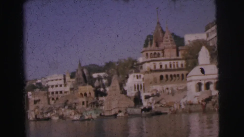 Hindu temples with shikhara spires and white domed structure above ghat steps, figures at waterline, Calcutta, India, 1962, 8mm film.