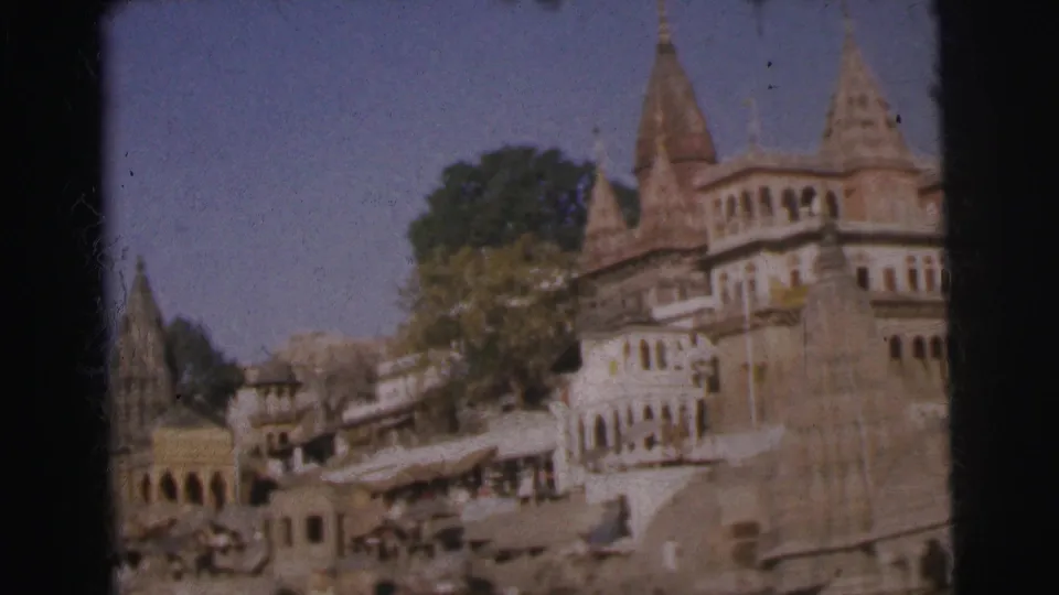 8mm colour frame, c. 1962, final position of a river-based pan showing a prominent temple tower and multi-storey arched buildings of an Indian ghat.