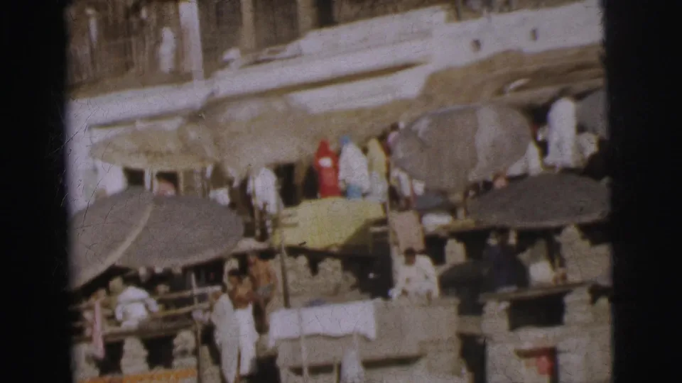 Worshippers and vendors on terraced stone ghat steps under shade canopies, Calcutta riverside, circa 1962, 8mm colour film.