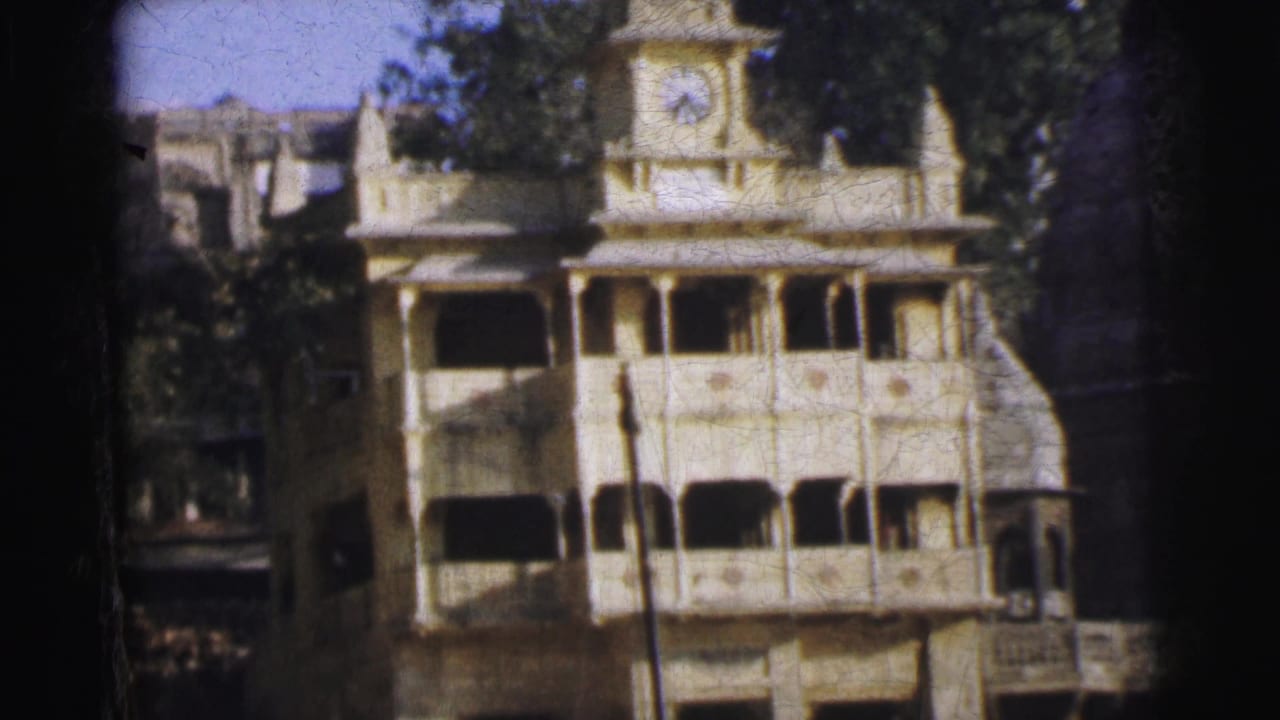 Multi-storey ochre building with clock tower and arched balconies, shot on 8mm film.