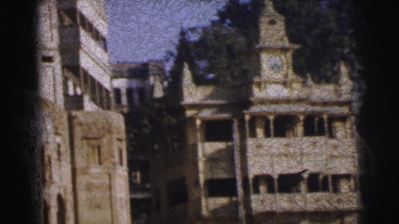 Multi-story colonial-style building with clock tower and arched balconies, filmed on 8mm.