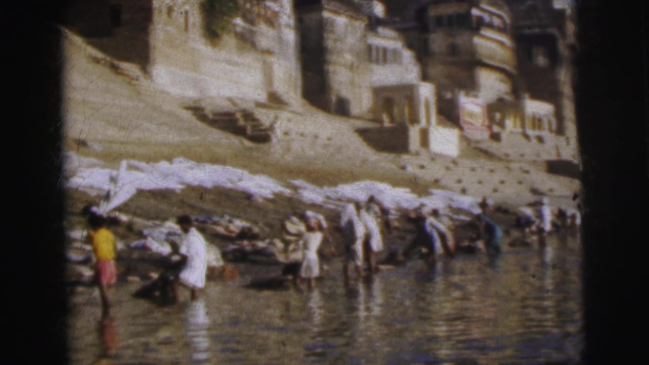 Wide view of a river ghat, Calcutta, India, 1962 — washers in traditional dress work at the waterline with white fabrics on stone steps and terraced buildings above.