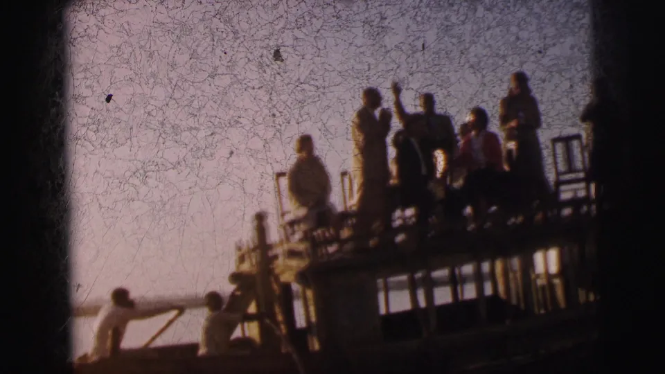 Closer framing of the platform boat group in Calcutta circa 1962; heavy film scratches and crackle overlay the scene, with one figure appearing to gesture with a raised arm.