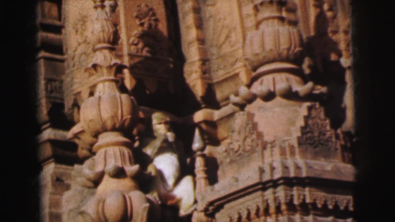 8mm close-up of a stone temple facade in Calcutta, India (1962), showing tiered carved pillars and a monkey amid the sculptural stonework.