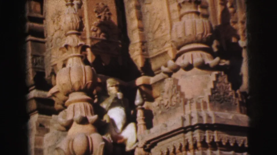 8mm close-up of a stone temple facade in Calcutta, India (1962), showing tiered carved pillars and a monkey amid the sculptural stonework.