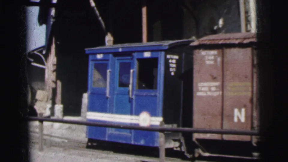 8mm film circa 1962, India: a compact blue passenger or guard's railcar with white horizontal stripe sits at a narrow-gauge yard beside a brown freight wagon marked N.