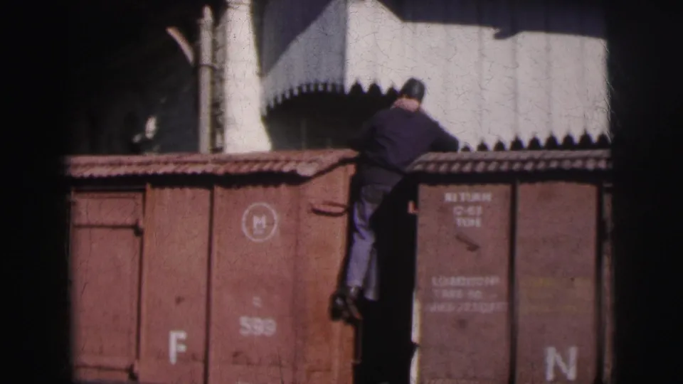 Worker climbing freight wagon at Calcutta railway yard, c.1962; car bears stenciled weight and capacity markings consistent with Indian Railways notation.