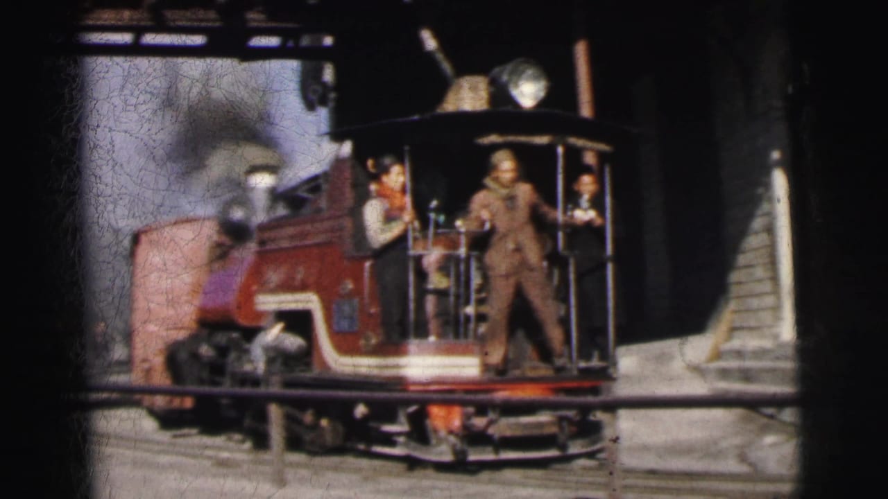 Red steam locomotive navigating a yard curve in Calcutta, India, circa 1962; two crew members in work attire stand on the open cab platform.
