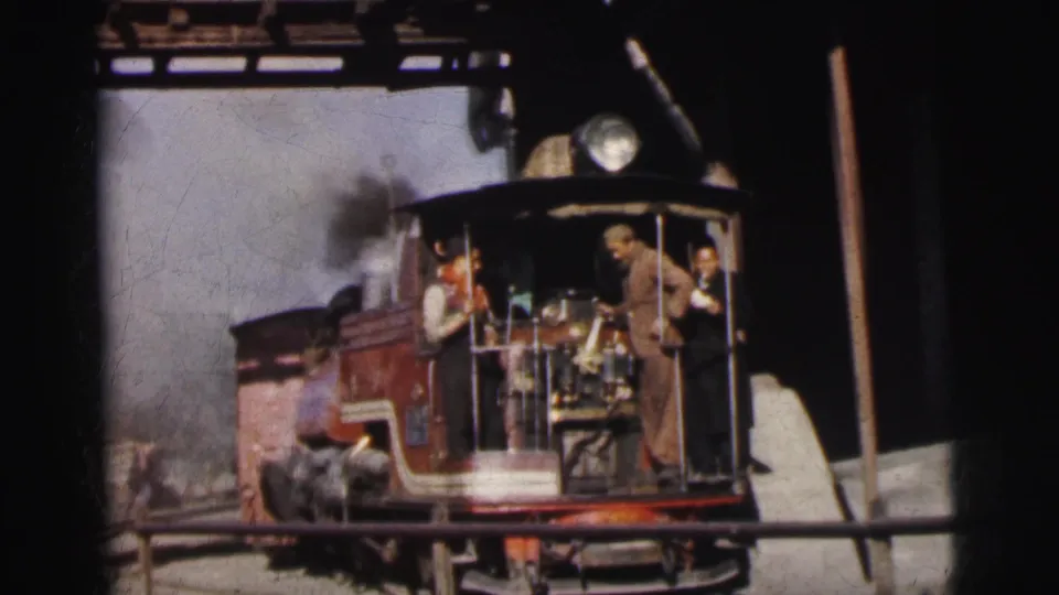 Close-up of dark-red narrow-gauge steam locomotive with crew in open cab, Calcutta India circa 1962, 8mm home movie