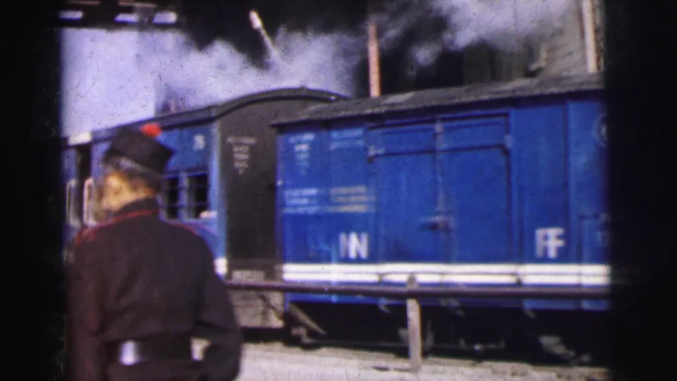 Railway worker viewed from behind beside blue passenger rail coaches with painted letter markings, 8mm colour film, India c.1962.