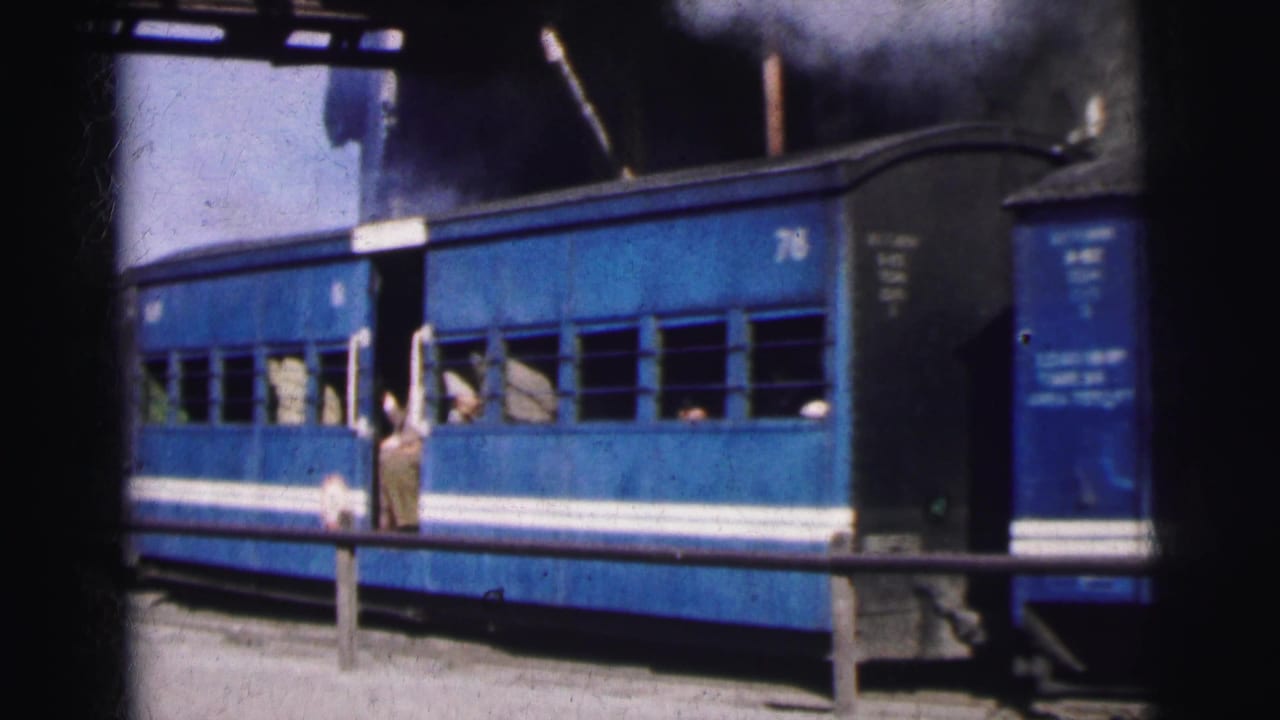 Blue passenger coaches at a mountain station with a figure near the carriage door and open windows, 8mm colour film, India c.1962.