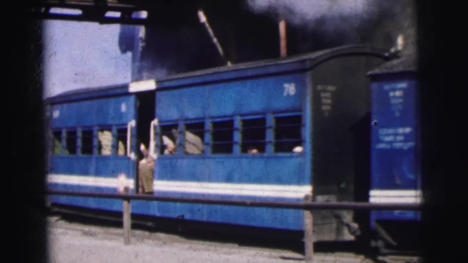 Blue passenger coaches at a mountain station with a figure near the carriage door and open windows, 8mm colour film, India c.1962.