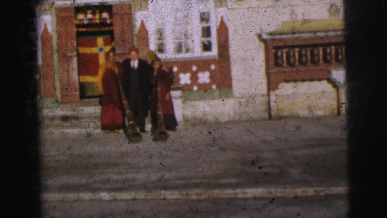 Two maroon-robed figures flank a man in dark coat and red hat at an ornate building entrance, Calcutta, 1962; geometric wall motifs visible.