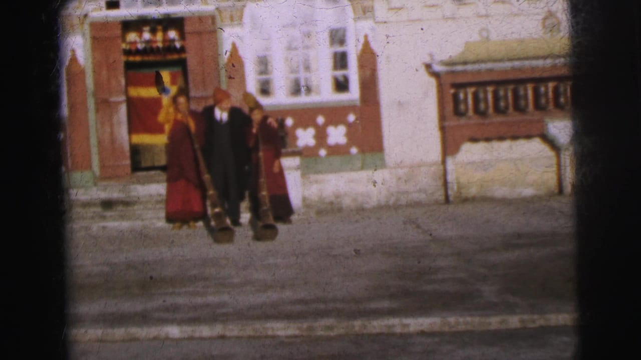 Same three figures at the monastery entrance, slightly repositioned; decorated doorway and wooden awning structure visible behind them.