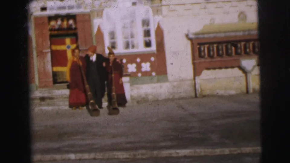 Three figures at a monastery-style entrance in Calcutta, 1962; two in maroon robes flank a man in dark coat; aged film color cast throughout.