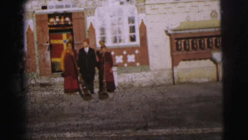 Final 8mm color frame circa 1962 of three figures in ceremonial robes and suit before a decorated building exterior, Calcutta.