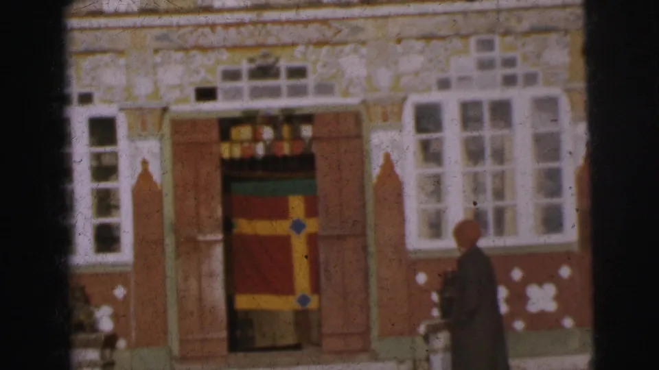 Exterior of ornate building in Calcutta, circa 1962; a figure walks past the colourfully banded doorway, visible at lower center of frame.
