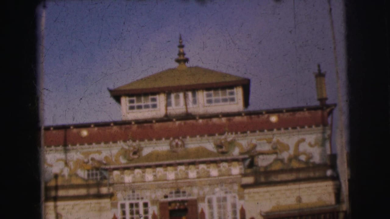 Multi-story decorated building facade with tiered rooftop pavilion against blue sky, showing yellow, red, and white painted ornamentation
