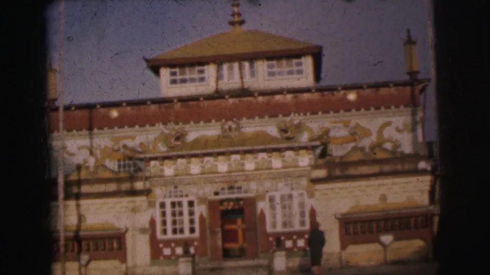 8mm frame from 1962 Calcutta; lower facade of ornate building emphasizing gold animal-motif reliefs on red band; tiered roof above and figure near the entrance below.