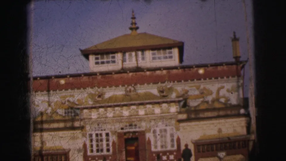 8mm frame from 1962 Calcutta; full facade view of ornate building with pagoda-style tiered roof, gilded carvings on red frieze, and a figure near the entrance.