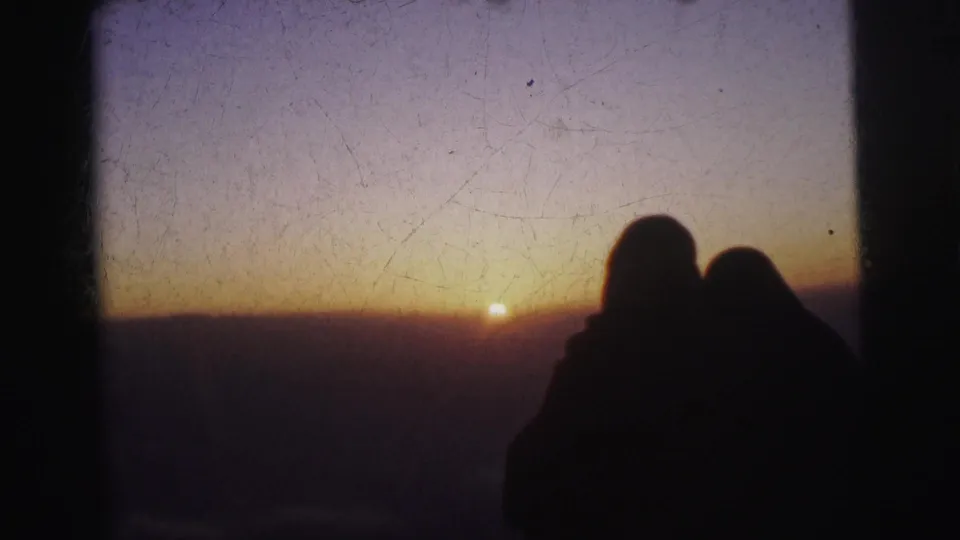 At the end of the clip, the silhouetted pair appears near the right edge while the sun remains low over the horizon in this 1962 Calcutta 8mm home-movie frame.