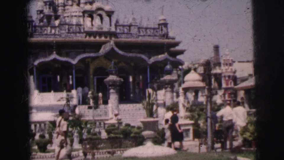 1962 home-movie view of tourists near steps, statues, and garden features at an ornate Indian landmark complex.