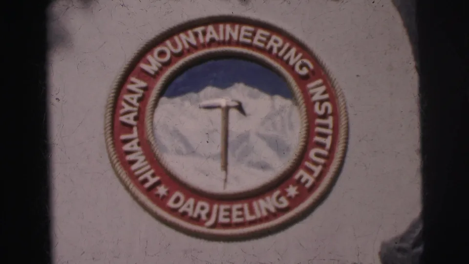 Close view of a Himalayan Mountaineering Institute Darjeeling emblem, with an ice axe over a mountain motif.