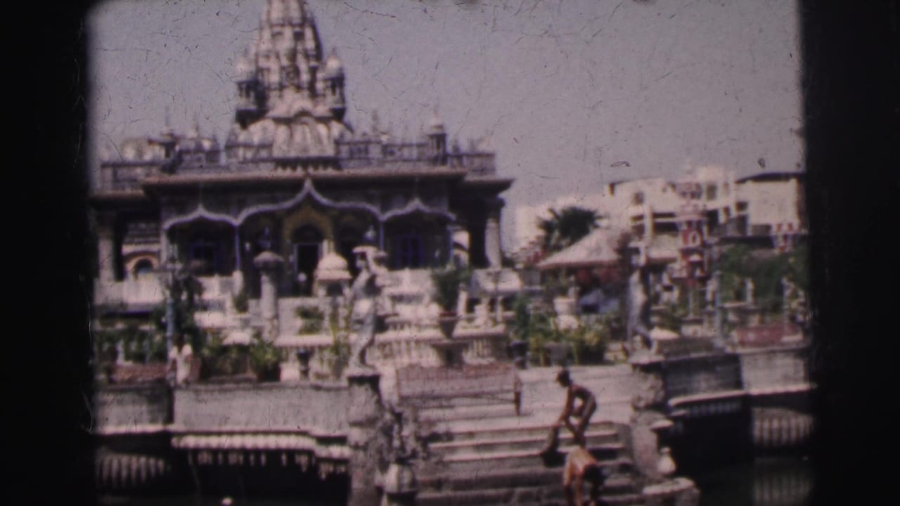 Ornate temple exterior with steps, railings, garden details, and small figures nearby.