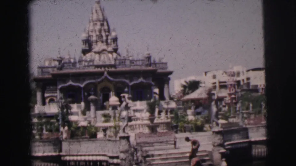 1962 Calcutta frame of the temple exterior, showing the tower, arched entrance, stone railings, and visitors in the foreground.