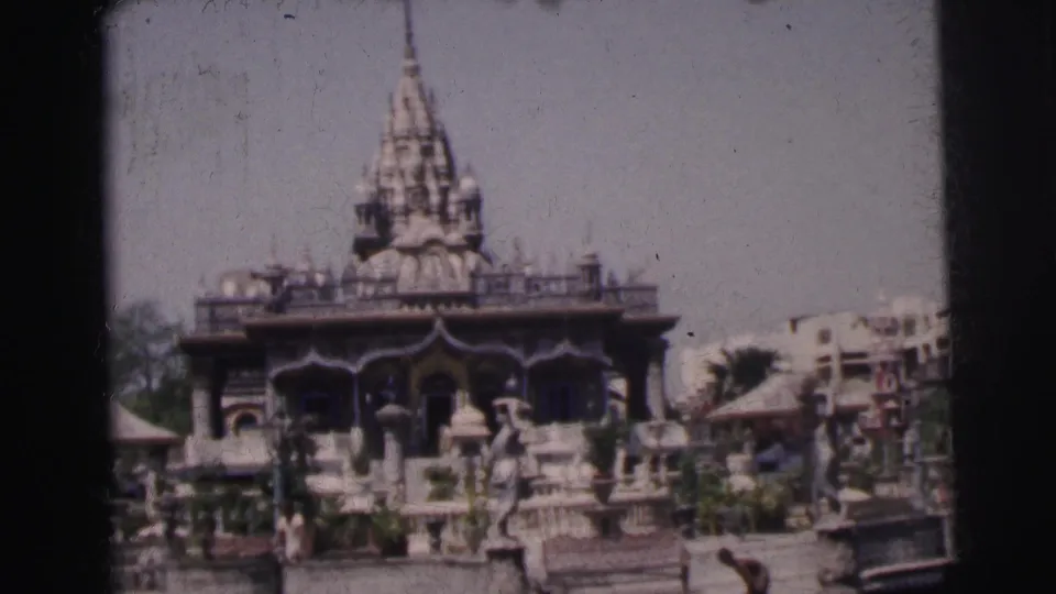 1962 Calcutta home-movie view of an ornate temple across stone steps, railings, plantings, and scattered visitors.