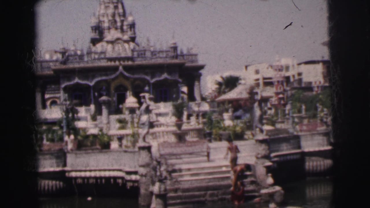 Temple facade with water, steps, railings, and people on the lower platform.