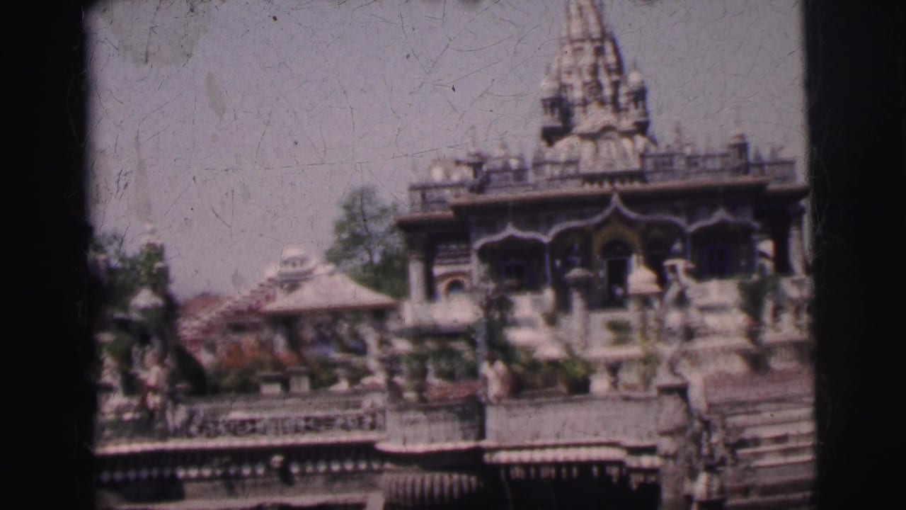 Ornate Indian temple complex with prominent carved spire, decorative stone pavilions, and stepped base, similar framing to preceding shot.