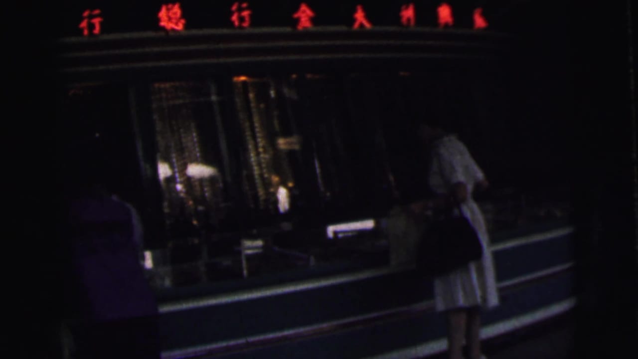Dim storefront view with a woman in white near a glass display and red Chinese characters above.