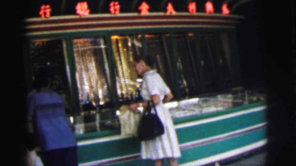 The final 1962 Calcutta frame shows the woman facing the storefront display as the man in blue remains beside the green-trimmed window.