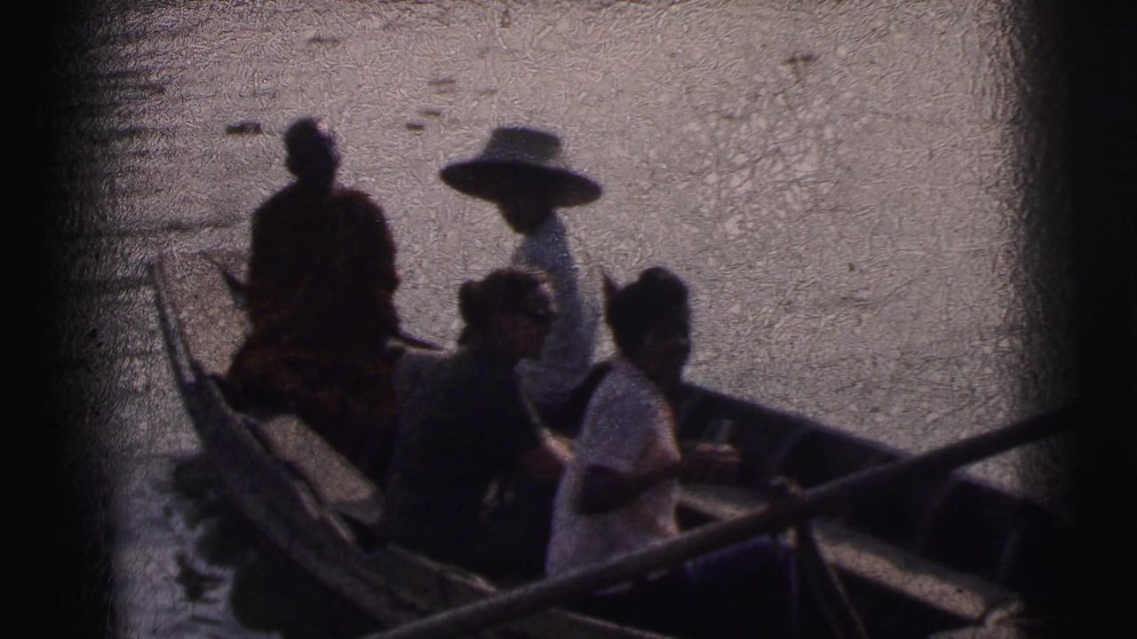 Passengers in a wooden boat in Calcutta, with a robed figure forward and paddles visible across the frame.