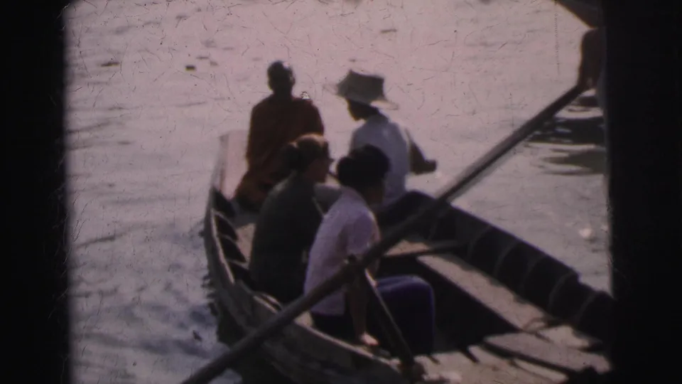 1962 Calcutta river-boat frame showing seated passengers, including a robed figure, in a narrow wooden boat.