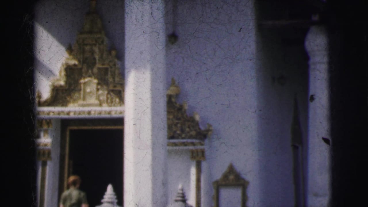 A visitor stands near a white column and dark temple doorway below ornate decoration.