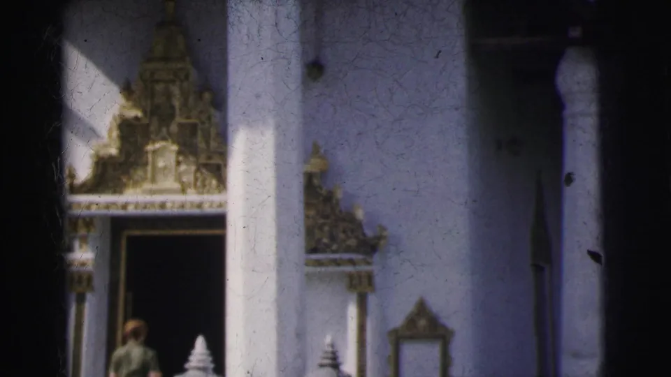 1962 Calcutta frame of a visitor near a white temple entrance, with a column, dark doorway, and gilded architectural detail visible.