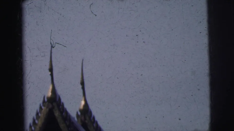 1962 Calcutta frame showing two slender temple spires and part of a roofline silhouetted against a pale, scratched film sky.