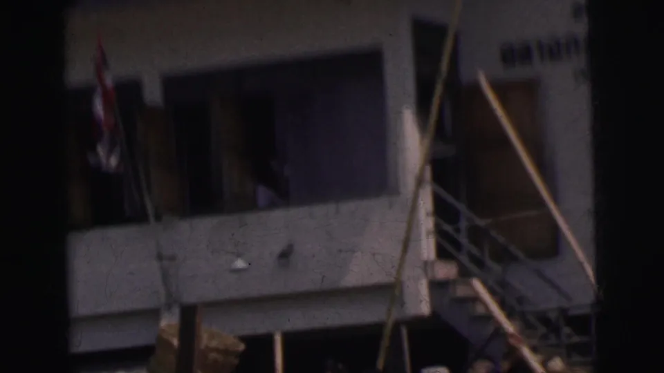 1962 Calcutta home-movie frame showing pedestrians near a building entrance with stairs, railings, and soft handheld focus.
